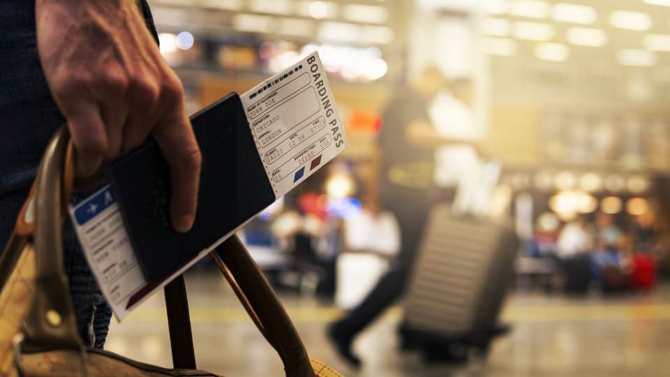 tay cầm hộ chiếu và vé máy bay đứng giữa sân bay